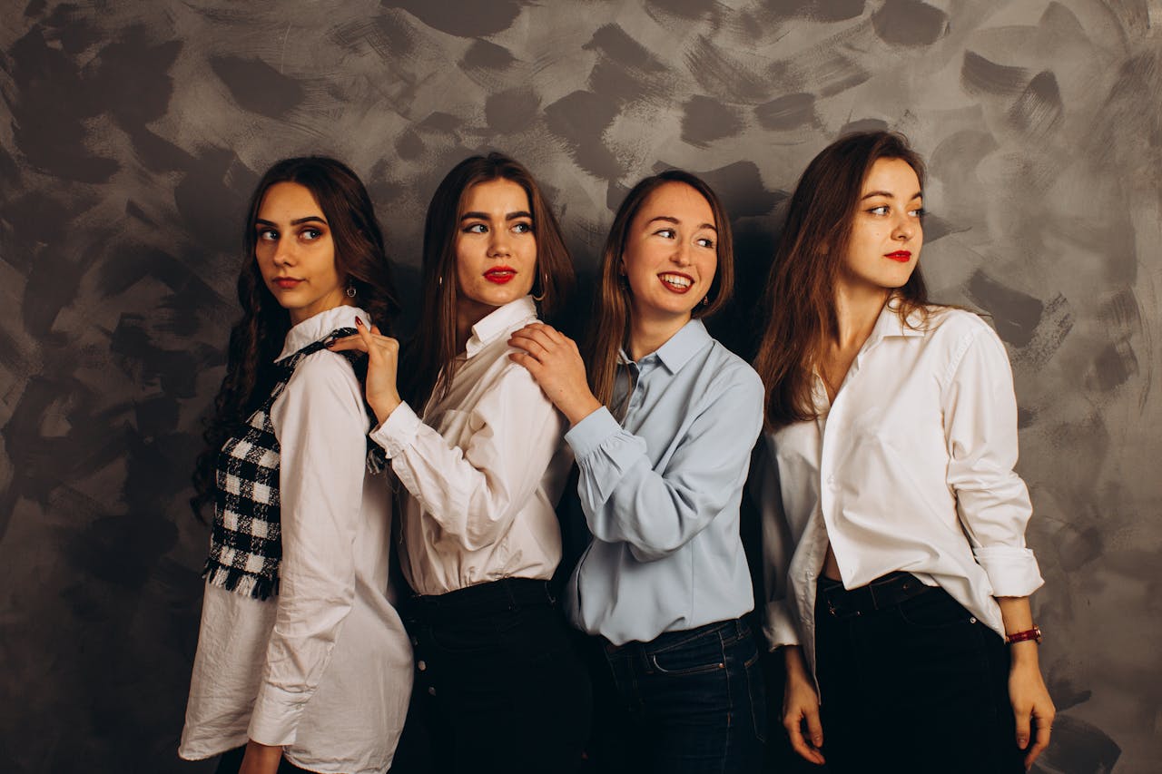 Four women in fashionable casual attire pose elegantly in a studio shoot.